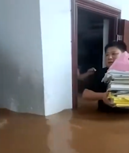 广西贵港受强降雨一中教师在齐腰高的深水中转移教材，有人用大盆转移妇孺